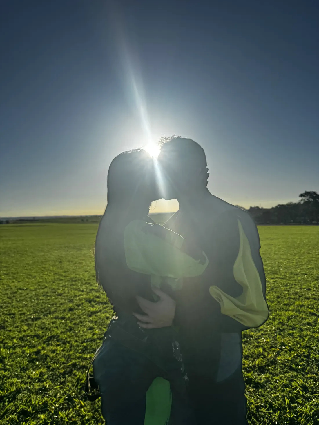 Felipe e Lana se beijando contra o sol, num campo aberto